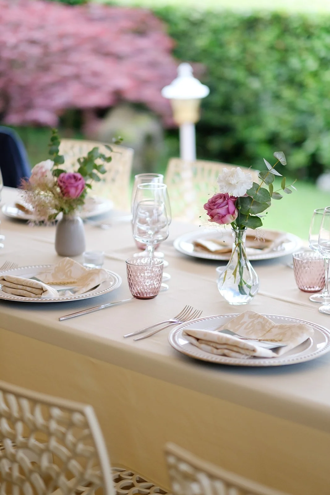 Tavolo apparecchiato in giardino con rose rosa, eucalipto e bicchieri rosati Tavolo apparecchiato in giardino con rose rosa, eucalipto e bicchieri rosati